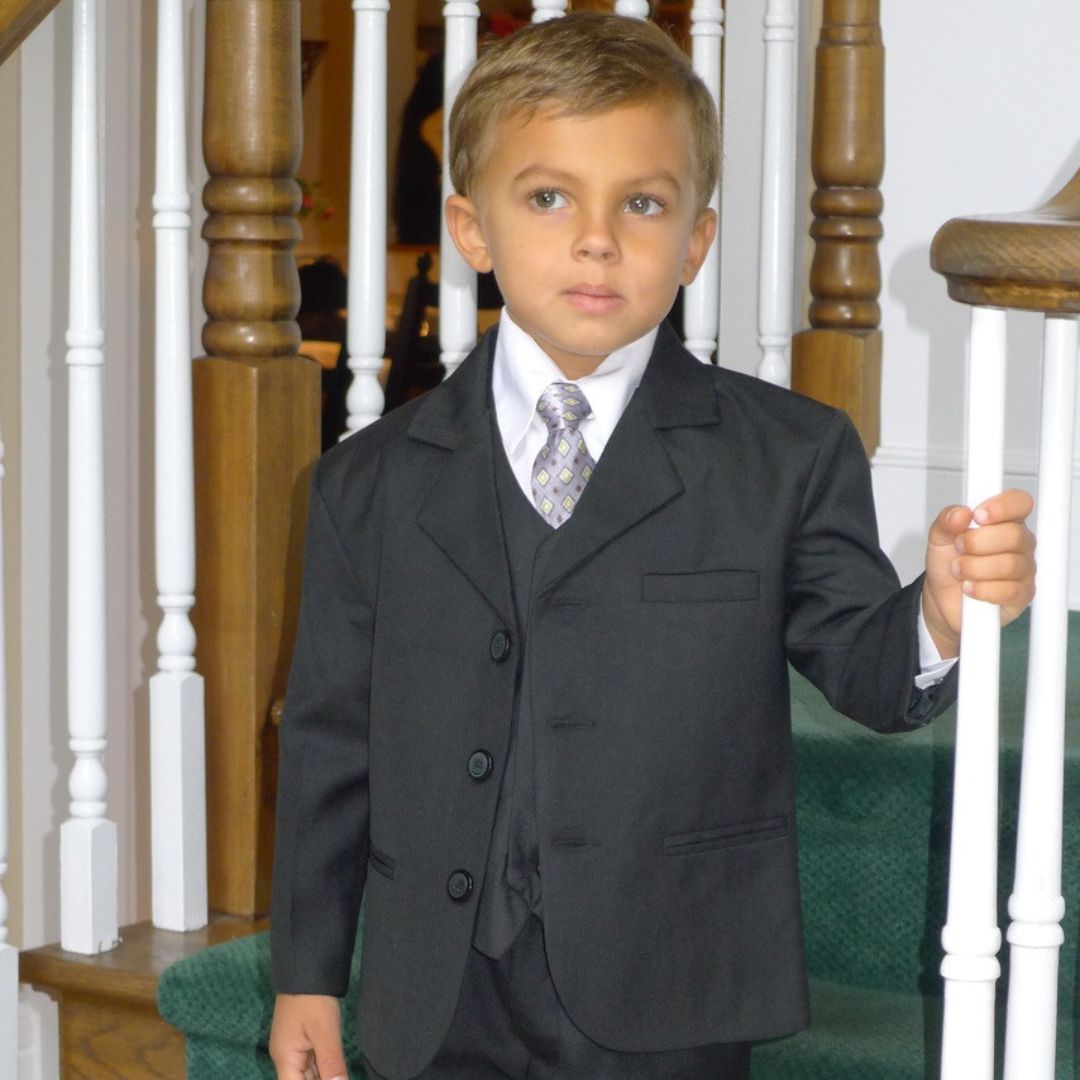 Boy in a black communion suit standing on a staircase